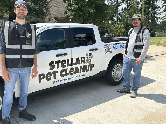 Two Stellar Pet Cleanup crew members in safety vests standing beside the wrapped company truck in a customer's driveway